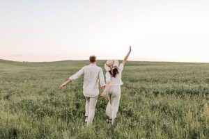 Coppia felice che corre in un campo d'erba 